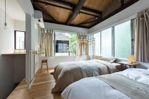 A modern bedroom with wooden furniture, white bedding, and a natural light-filled space.