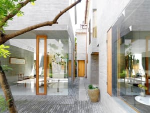 Contemporary interior design featuring a minimalist concrete space with large windows and a central courtyard.