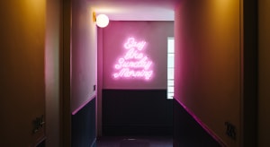 A pink neon sign with the phrase 'Easy like Sunday Morning' in a minimalist interior setting.