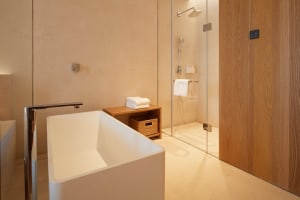 Modern bathroom with concrete walls, a white bathtub, and a glass shower enclosure.