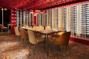 A modern wine tasting room with a long table set with wine glasses and bottles.