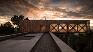 A minimalist residential building with bamboo exterior overlooking the sunset sky.