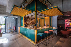 An industrial-style restaurant bar with metal clad modules featuring colorful seating and a well-stocked bar.