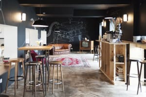 Industrial-style coffee shop with wooden furniture, vintage television, and abstract wall mural.