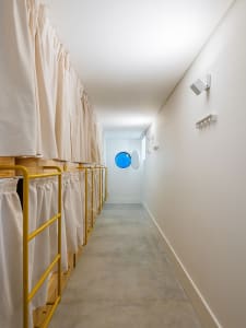 A minimalist dormitory hallway with curtains and yellow steel railings.