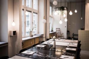 A modern office space with white marble tables and pendant lights.