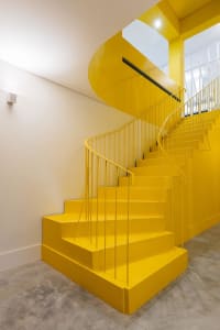 Modern interior with a bright yellow staircase painted with concrete materials.