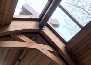 A close-up view of a modern wooden truss roof structure with glass panels.