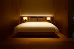 Minimalist bedroom with a white bed and wooden walls.