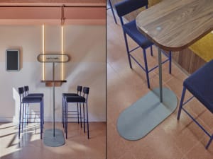 A modern cafe interior with blue furniture, wooden tables, and metal stools.
