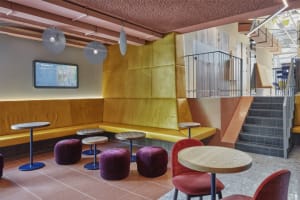 A modern cafe interior with yellow leather seating and round tables.