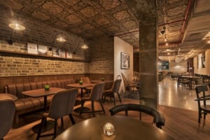 Industrial-style restaurant with brick walls, leather booths, and wooden tables.