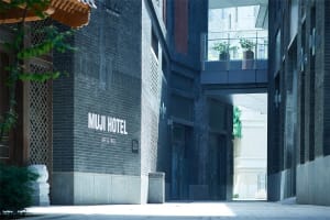 MUJI Hotel exterior with a brick wall and large windows.