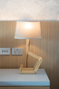 A wooden adjustable table lamp with a beige lampshade on a wooden surface.