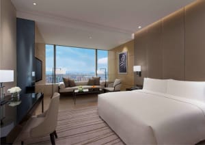Modern hotel bedroom featuring contemporary furniture and a view of the cityscape.
