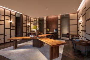 A modern office setting featuring a live-edge wood desk with leather chairs and glass partitions.