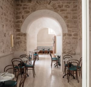 Modern minimalist cafe interior featuring stone walls and concrete flooring.