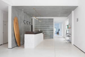 A modern reception area featuring a concrete and white wood desk, with clocks on a dark grey wall.