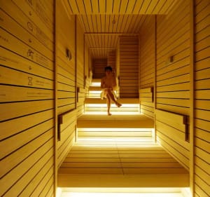 A person sitting in a modern wooden sanctuary illuminated by warm lighting.