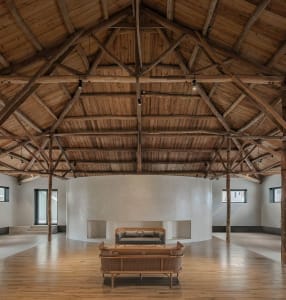 Modern minimalist interior design featuring exposed wooden beams, a white wall, and minimalist furniture.