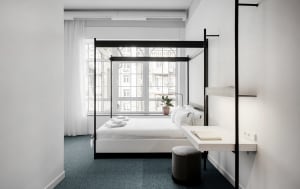 Modern minimalist bedroom with white bed and furniture.
