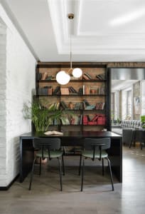 A modern home office with industrial design features, including exposed brick walls and dark wood furniture.