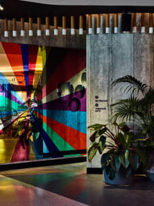 A modern hotel lobby featuring a colorful geometric installation on a concrete wall.