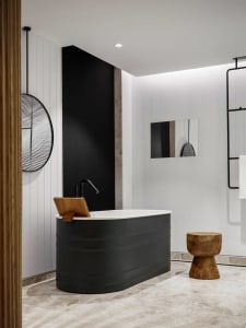 Modern bathroom featuring a black freestanding bathtub with wood accents and minimalist design elements.