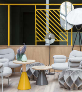 A modern living room featuring stylish furniture, a yellow table, and geometric design elements.