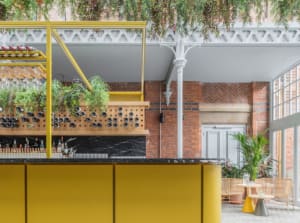 A modern restaurant bar with yellow walls, wooden elements, and stone accents.