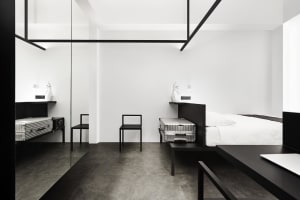 Modern minimalist bedroom featuring black and white decor with metallic luggage and furniture.