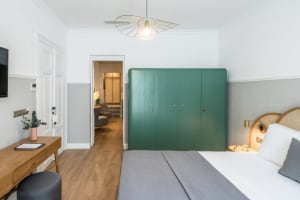 Interior design of a minimalist bedroom featuring gray furnishings and a green wooden cabinet.