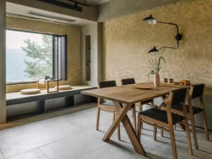 Modern dining room featuring a wooden table and chairs, with a view of mountains outside through a window.