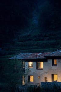 A rustic house with concrete walls and tiled roof in the evening