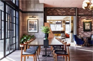 Industrial-style restaurant interior with brick walls, concrete flooring, and wooden furniture.