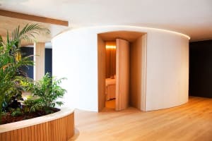 A minimalist spa treatment room with white walls and wooden flooring.