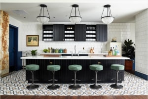 Modern kitchen with black cabinets, patterned tile flooring, and bar stools