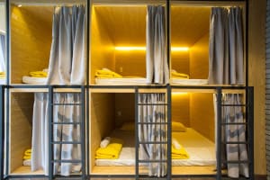 Striped bunk beds with yellow pillows and blankets in a modern bedroom with wood walls and floors.