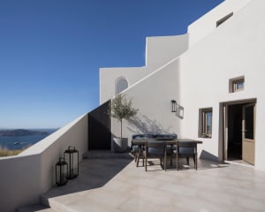 A minimalist white stucco exterior building with a small table and chairs on a terrace.