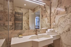 Modern bathroom with marble walls, a sink, and towels.