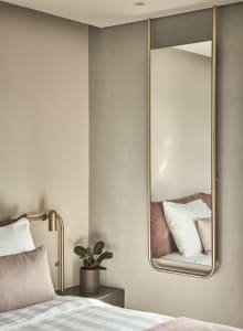 A sleek, modern bedroom featuring a mid-century mirror with a metallic frame.