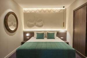 A modern bedroom featuring a textured bed and geometric wall design.