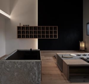 Minimalist design of a tea room featuring wooden seating and granite counters, showcasing clean lines and simplicity.