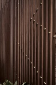 A close-up view of a wood-paneled wall with vertical slats and metallic accents.