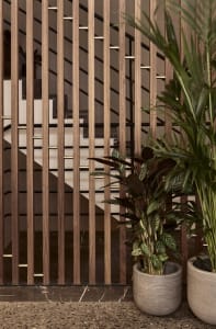 Modern lobby interior with wooden slatted wall and green potted plants.