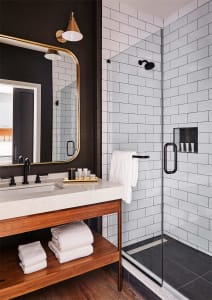 Modern industrial bathroom with white subway tiles, marble countertop, and wooden accents.