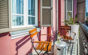 A modern residential balcony featuring wooden furniture, including a table, chairs, and a potted plant.