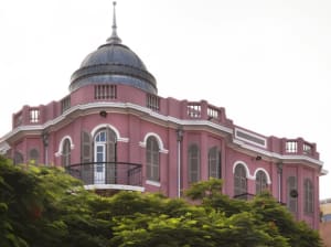 A pink residential building with a brick dome and arched windows.