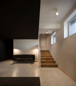 A minimalist stairwell with concrete and wooden stairs, featuring black and white color scheme and floor-to-ceiling windows.