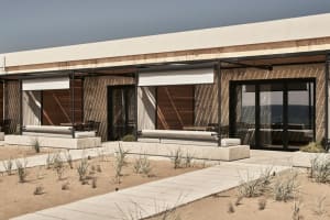 Modern, minimalist beachfront architecture featuring concrete materials and a spacious outdoor patio with comfortable seating